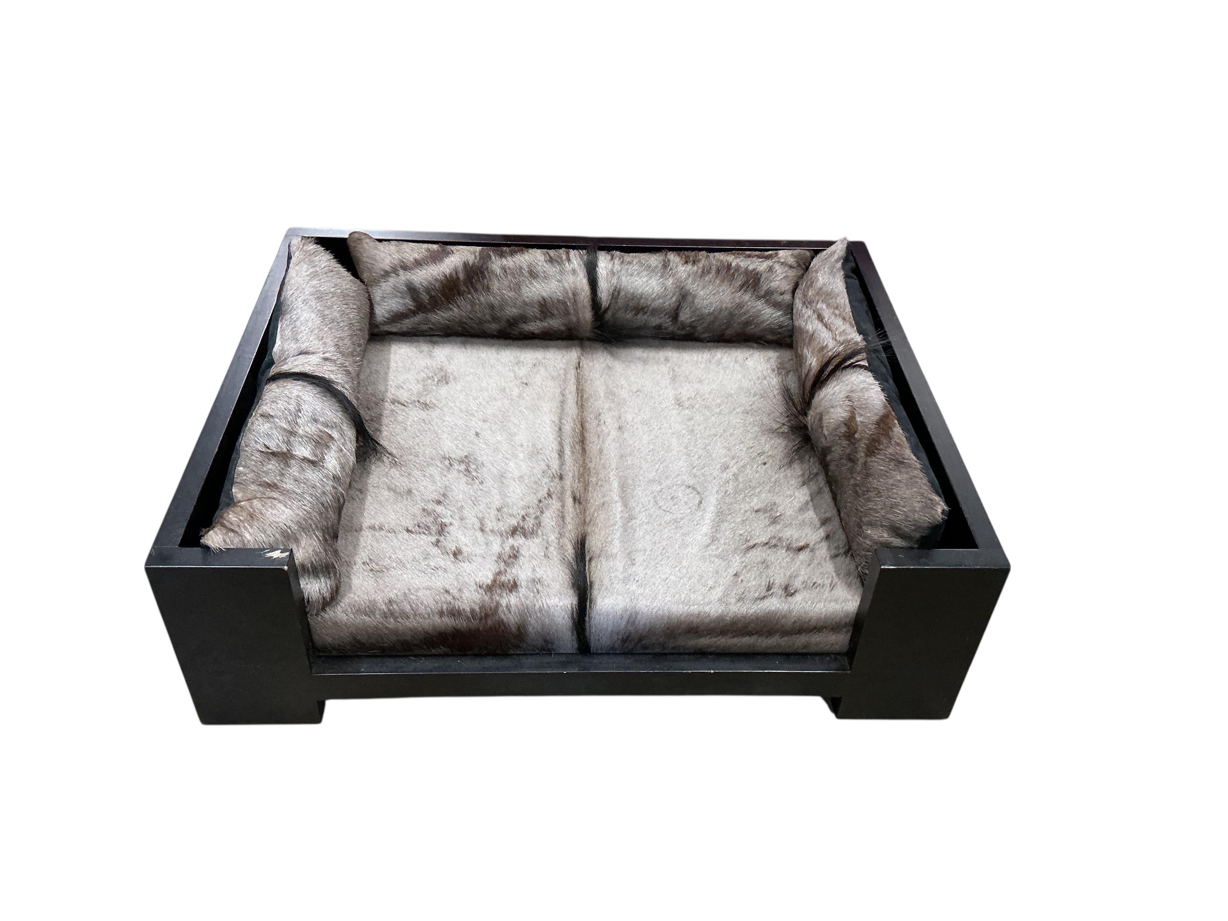 A contemporary ebonised dogs bed with faux fur cushions, width 97cm, depth 77cm, height 29cm